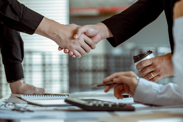 Businessmen shake hands and agree on a table On the desk after a long meeting.