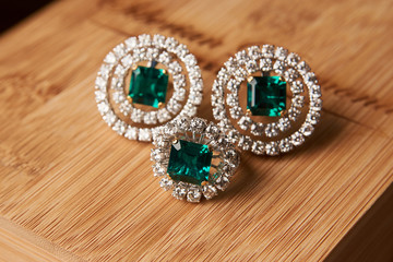 Emerald ring and pair of diamond earrings in gold, wedding jewelry with luxury gift box , close-up. Selective focus