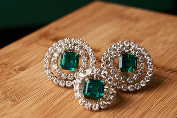 Emerald ring and pair of diamond earrings in gold, wedding jewelry with luxury gift box , close-up. Selective focus