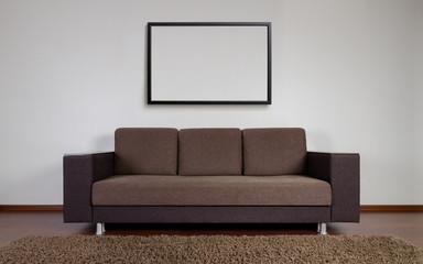 Modern couch with blank frame on the wall