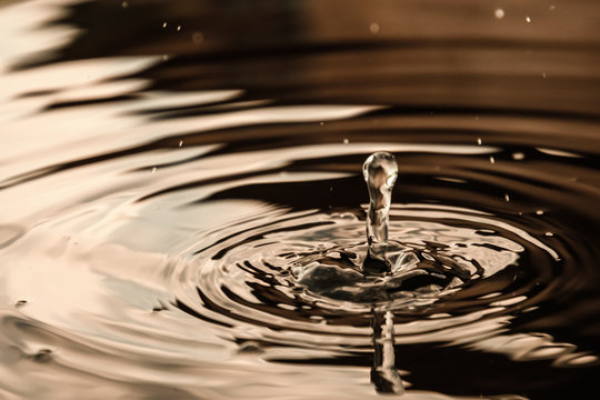 Circles on the water closeup with falling round drops, reflection warm colors