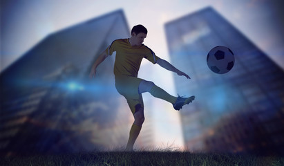Football player in yellow kicking against low angle view of skyscrapers