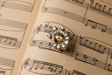 Gold brooch with diamonds in the form of a harp. Luxury female jewellery, close-up. Selective focus