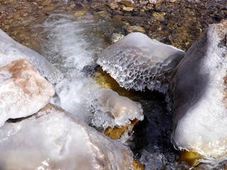 Photo of beautiful ice structures on top of rocks in a mountain river.