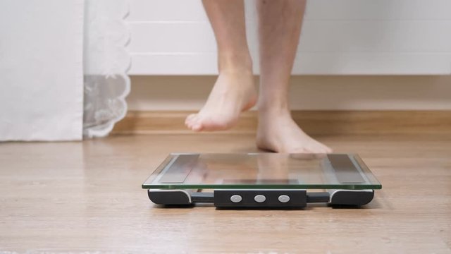 Man step on digital glass scales to check his weight. Jumping after successful weighing