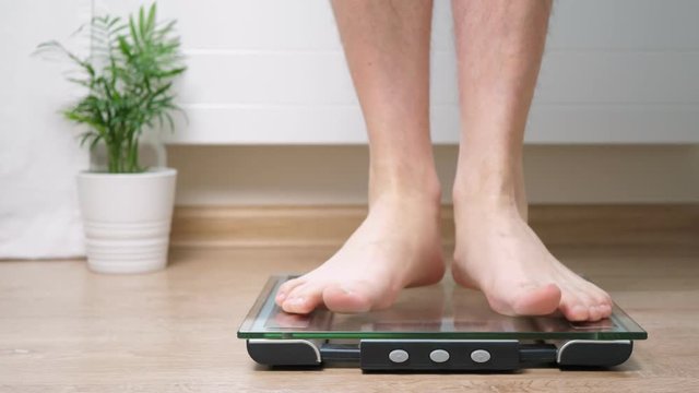 Man step on digital glass scales to check his weight