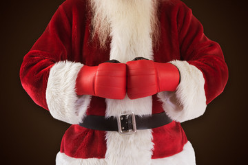 Santa Claus wears boxing gloves against dark brown background
