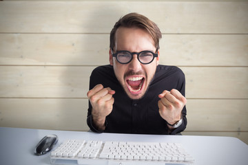 Businessman cheering in front of his computer against bleached wooden planks background
