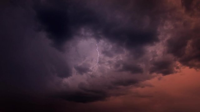 Time-lapse stormclouds in a red sky with forked lightning effects