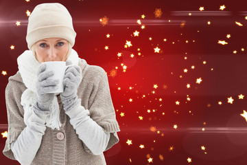 Woman in warm clothing holding mugs against bright star pattern on red