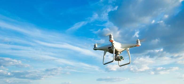 Fototapeta Drone flying overhead in cloudy blue sky