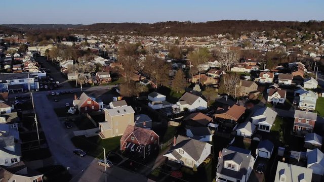An early Spring slow forward aerial establishing shot of a typical residential neighborhood in a Western Pennsylvania small town at dusk. Pittsburgh suburbs.  	