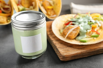 Tasty creamy sauce for fish taco in glass jar on kitchen table