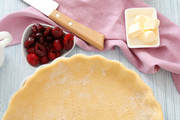 Baking pan with unbaked crust for cherry pie on kitchen table