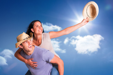 Fototapeta premium Man giving his pretty girlfriend a piggy back against bright blue sky with clouds