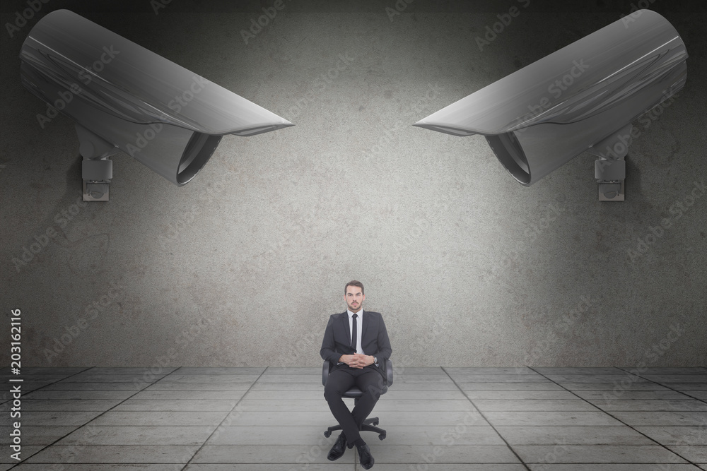 Poster Stern businessman sitting on an office chair  against grey room