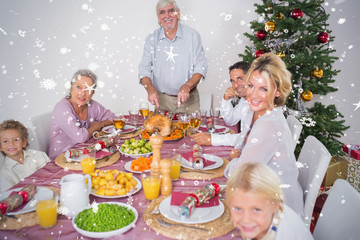 Composite image of Happy family at christmas dinner against snow falling