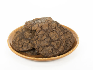 Homemade chocolate brownie cookies on an orange plate against a white background.