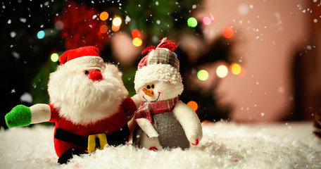 Snow falling against santa claus and snowman on snow