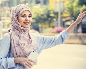 Islamic woman calling taxi in the city