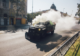 Riot police vehicle sprays tear gas to demonstrators during a demonstration.