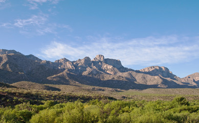 A distant mountain range in the Sonoran desert with a beautiful blue sky and a lush green valley