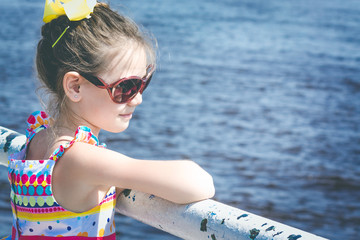 Beautiful child with glasses have a ship waiting on the pier