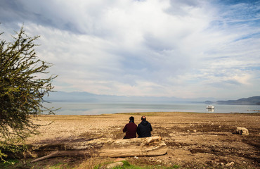 Father and son sitting on a old tree log, in reservoir Convento Viejo, Chimbarongo near Rancagua,...