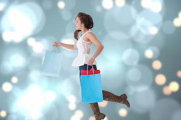 Happy brunette leaping with shopping bags against blurred lights