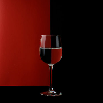 Glass wine glass on a black and red background. Mirror image. Different background colors. The red and the black by Stendhal