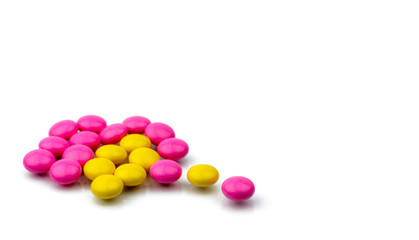 Pile of pink and yellow round sugar coated tablets pills isolated on white background with copy space. Colorful pills for treatment anti-anxiety, antidepressant and migraine headache prophylaxis.