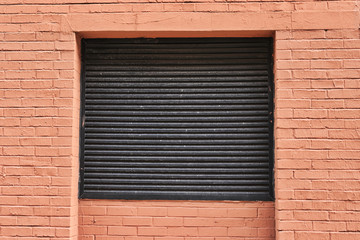 Brick wall and covered window in urban cityscape building.