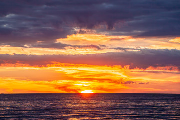 Fototapeta na wymiar Tranquil vivid sunset with glowing orange clouds and calm ocean water
