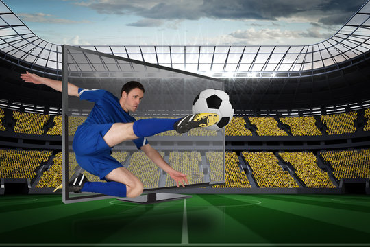 Composite image of football player in blue kicking ball out of tv against vast football stadium with fans in yellow
