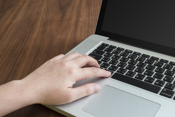 Woman hand press keyboard button of notebook computer on wooden table.