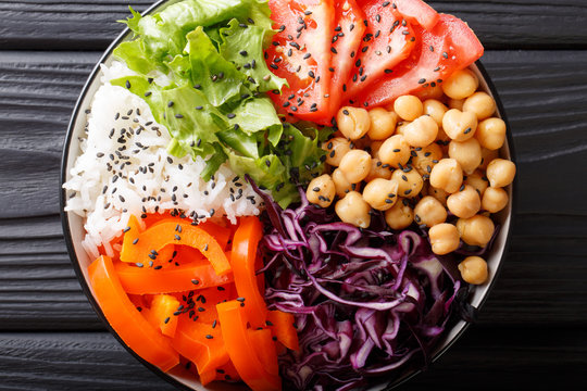 Freshly prepared Buddha bowl with red cabbage, tomatoes, lettuce, bell pepper, chickpeas and rice close-up. horizontal top view