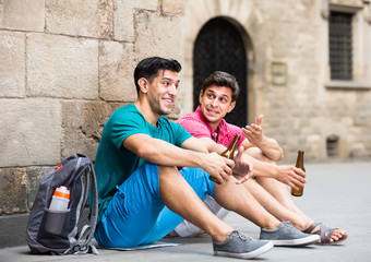 Relaxed male fans are drinking beer and talking about football outdoor in Barcelona