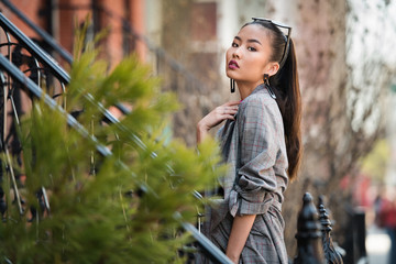 Beautiful asian fashionable young woman posing on city street outdoors