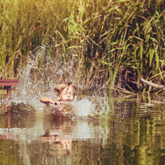 Young boy jumping, swimming and splashing in the river on summertime, image with square aspect ratio and warm toning