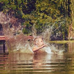 Young boy jumping, swimming and splashing in the river on summertime, image with square aspect ratio and warm toning