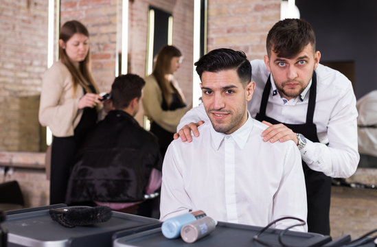 Hairstylist presenting result of his styling to male client