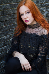 Stylish young beautiful red-haired girl near the stone wall - 203176924