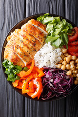 Salad Buddha bowl with chicken grilled, vegetables, chickpeas, rice and lettuce close-up. vertical top view