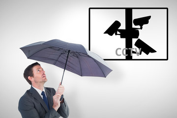 Businessman sheltering under black umbrella against cctv