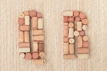 Alphabet letter Q and R made of wine corks on jute rope background