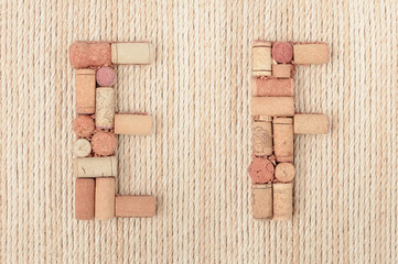 Alphabet letter E and F made of wine corks on jute rope background