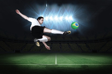 Fototapeta na wymiar Football player in white kicking in a football pitch under spotlights