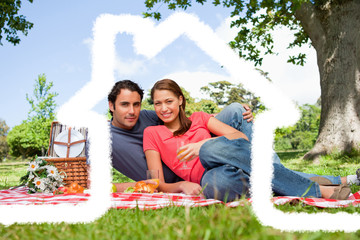 Two friends looking ahead while they hold glasses as they have a picnic against cloudy sky