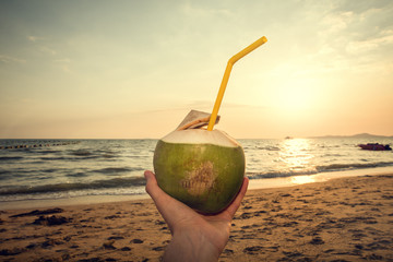 Coconut in hand on the beach. Sunset.
