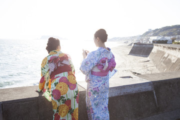 浴衣女性たちは堤防から海を見ている